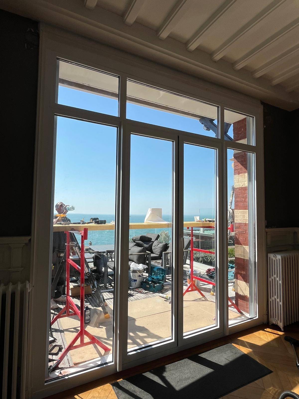 Installation d'une grande porte-fenêtre en alu blanc sur-mesure au Havre secteur plage : porte-fenêtre battante avec fixes latéraux et impostes